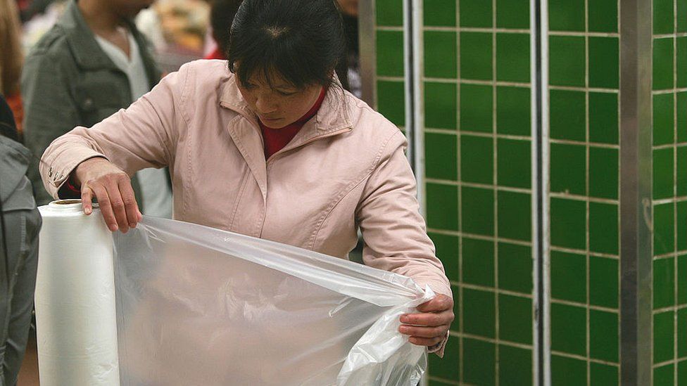 A customer gets a free thin plastic bag from a supermarket in Chongqing, China.