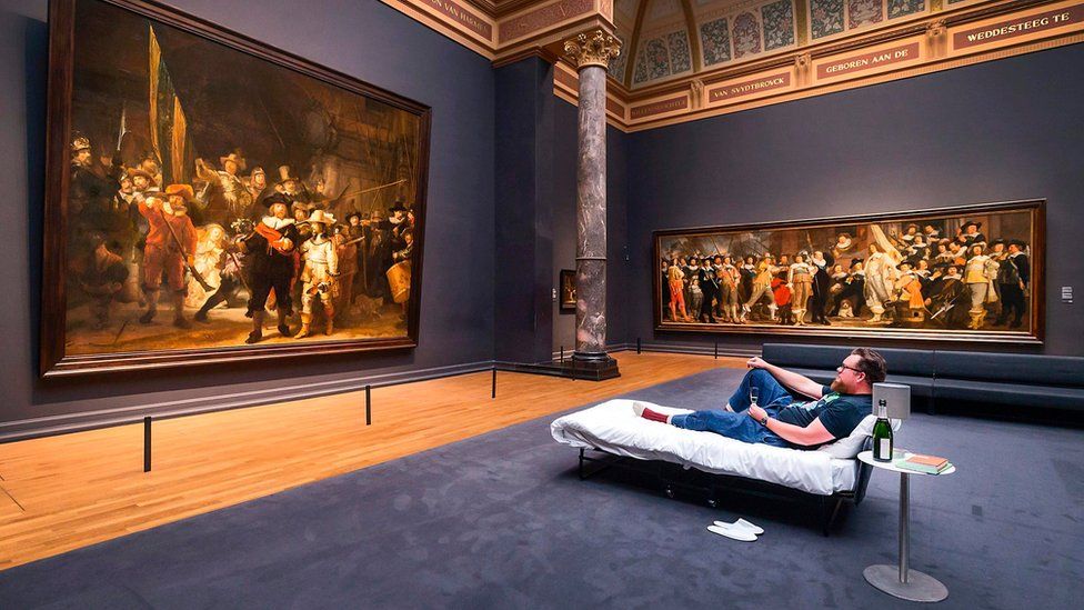 Stefan Kasper lying in a bed in front of the painting "The Night Watch" by Dutch painter Rembrandt at the Rijksmuseum of Amsterdam on June 1,