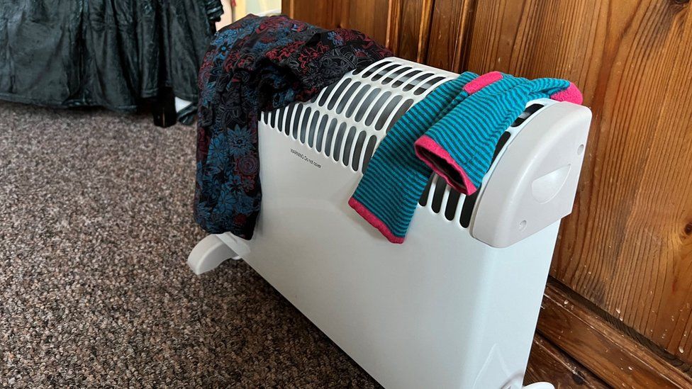 A white electric heater with socks and clothes drying on it
