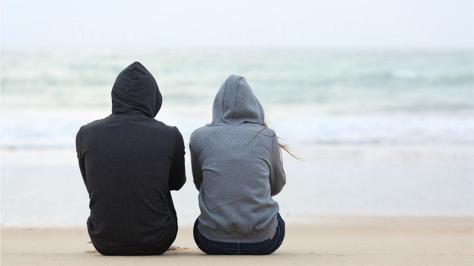 Two teenagers wearing hooded tops with their backs to the cameras