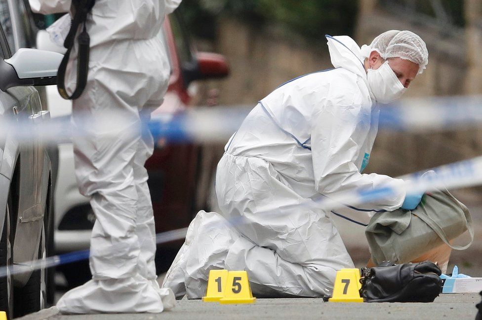 Forensic officers examine objects at the scene
