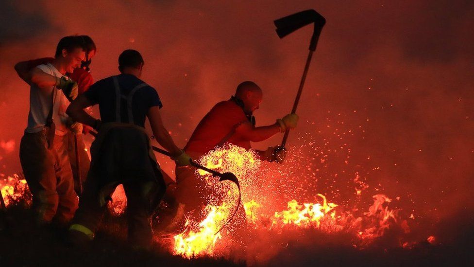 Firefighters tackle a wildfire with beaters on Winter Hill near Bolton. 28 June 2018.