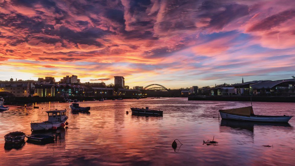 Sun setting with purple and red clouds over the water at Sunderland