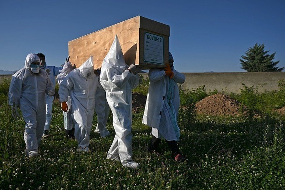 Workers in protective suits take away a coffin carrying the body of a Covid-19 victim in India (file photo)