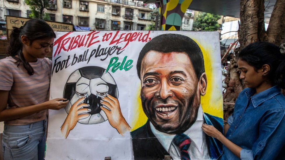 People hold up a sign for Pele at his funeral