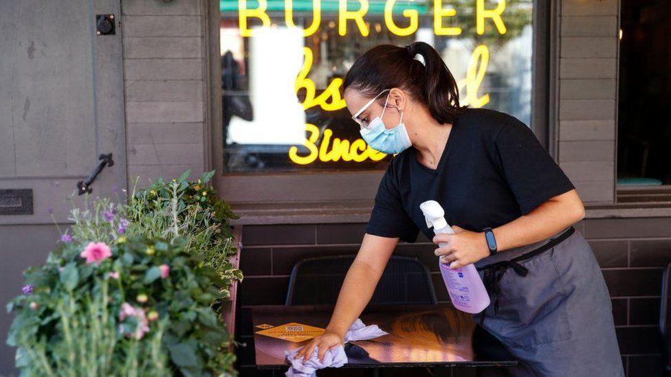Woman wiping table at burger restaurant