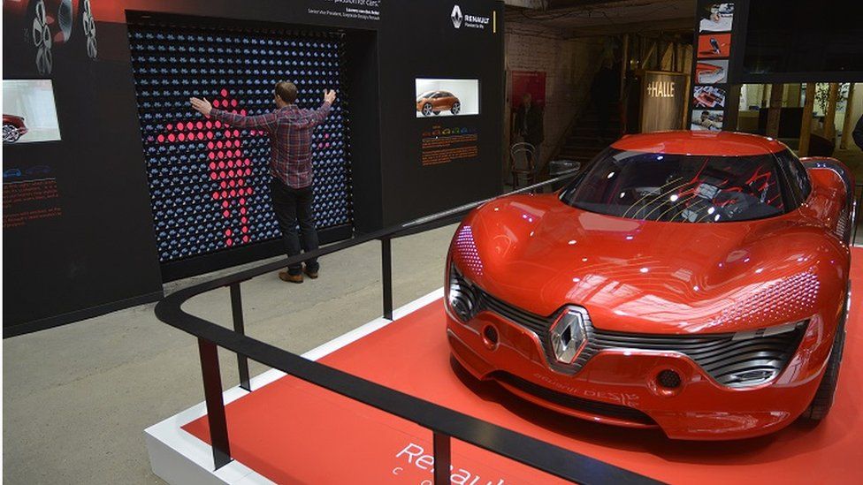 Renault Dezir electric car and man standing in front of light wall