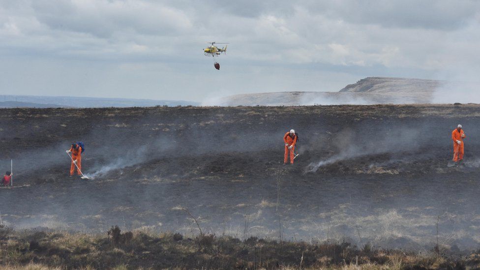 A helicopter drops water on the fire