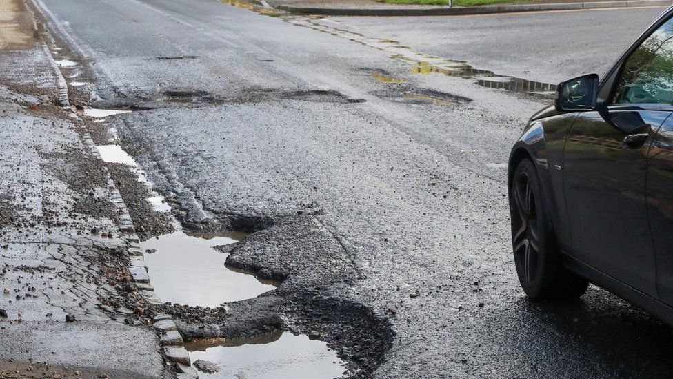 A car next to a pothole in Slough