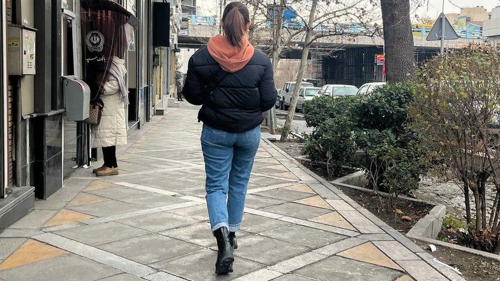 A picture of Bahareh walking down a street without a headscarf