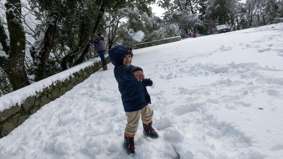 A child plays with snow in Redwood City in northern California