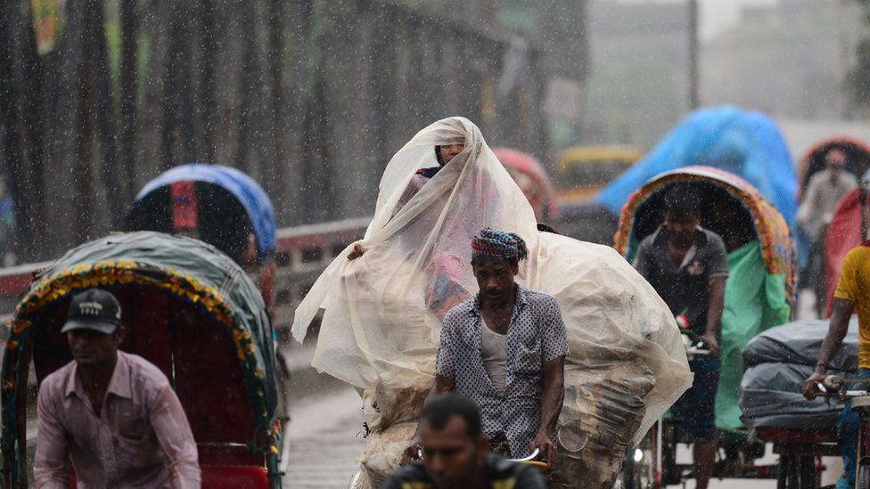 Bangladeshi rickshaw pullers make their way with commuters during a monsoon rain in Dhaka on 11 June 2017