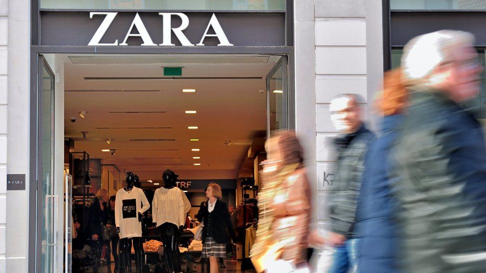 Shoppers walking past the entrance to a Zara store.