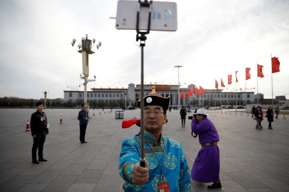 An ethnic minority man poses for a selfie on Tiananmen Square outside the Great Hall of the People ahead of the opening session of the National People's Congress in Beijing, 5 March