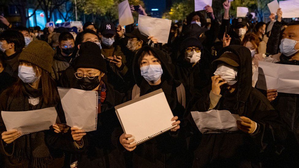 Demonstrators hold white signs as a form of protest during a protest against Zero Covid in Beijing