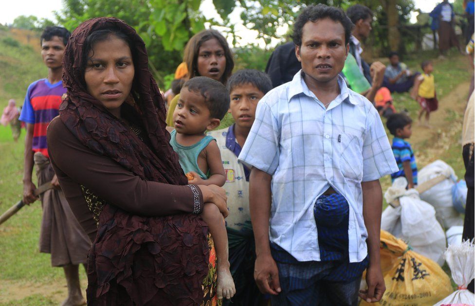 Rasida, who is nine months pregnant, waits with her family as they look for a space to set up their makeshift home