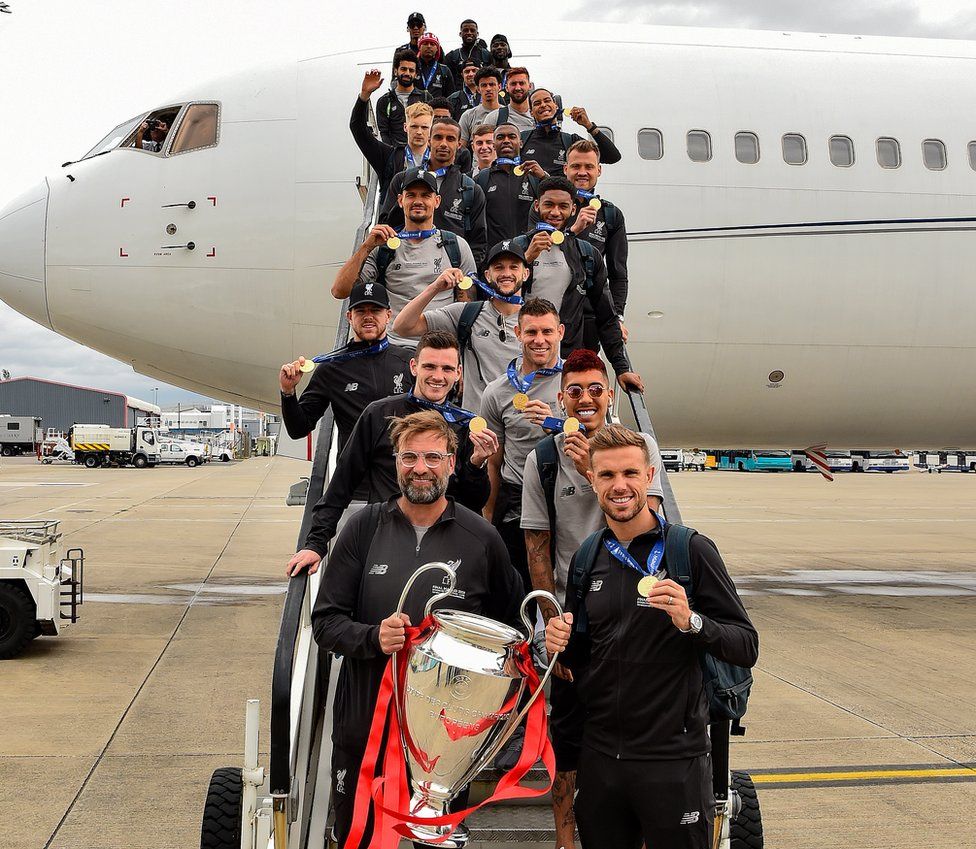 Jurgen Klopp and players with trophy as they come out of plane