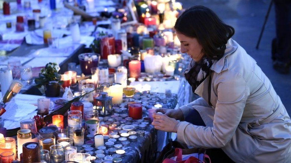 Woman lights candle at Paris memorial
