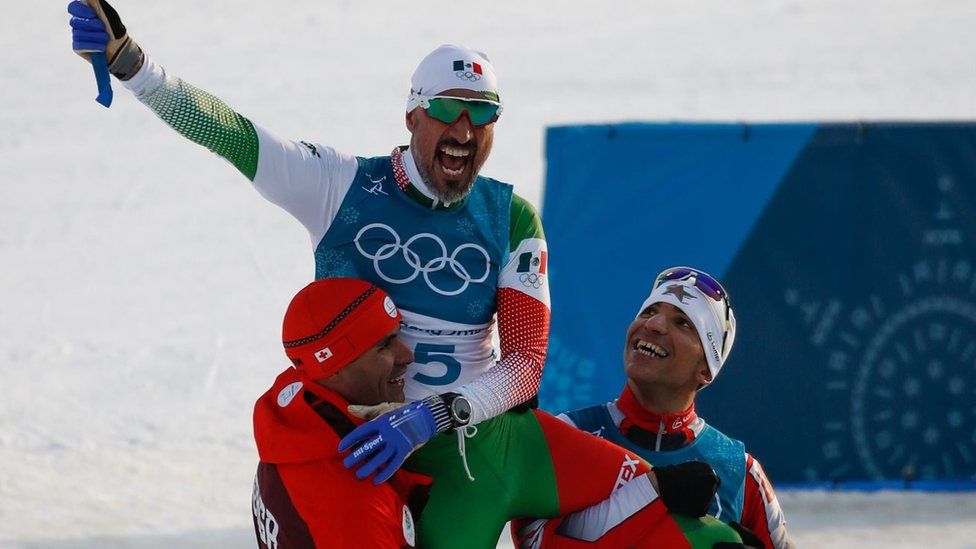 Tonga's Pita Taufatofua (L) and Morocco's Samir Azzimani (R) lift Mexico's German Madrazo onto their shoulders as they celebrate at the finish line in the men's 15km cross country freestyle at the Alpensia cross country ski centre during the Pyeongchang 2018 Winter Olympic Games on February 16, 2018 in Pyeongchang