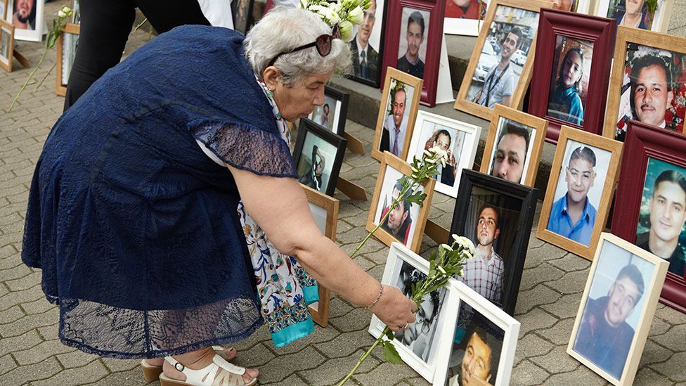 Woman lays flowers by photo of missing relative at an event in Berlin