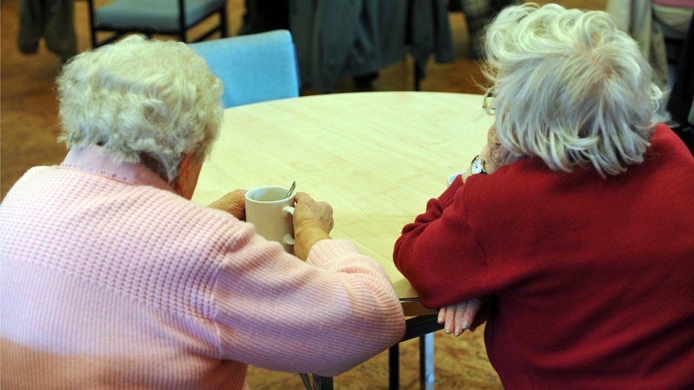 Two elderly ladies sat at a table
