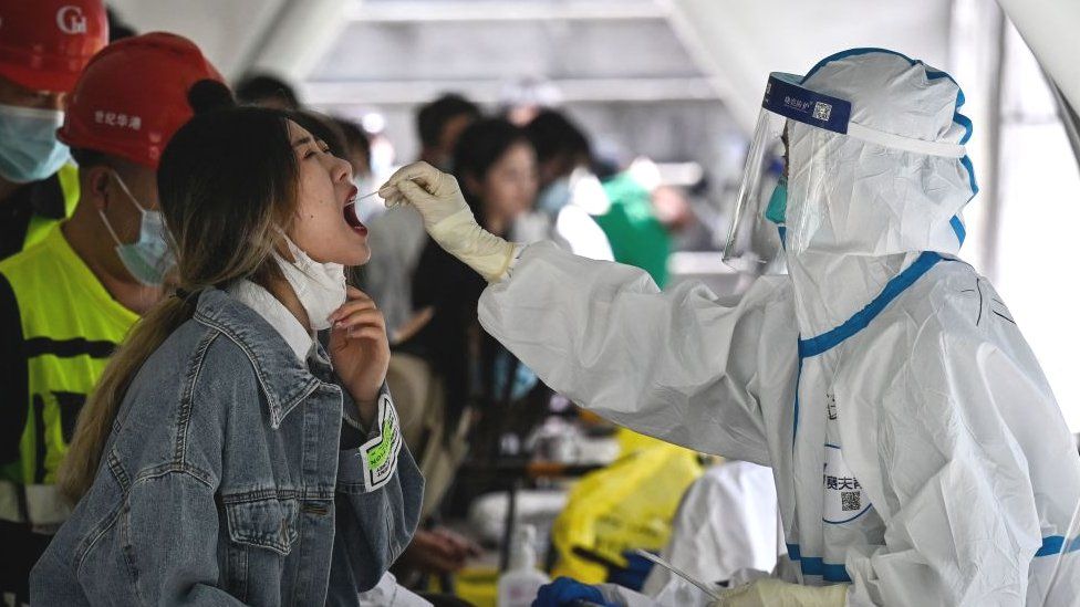 Медицинский работник берет образец мазка на Covid-19 у женщины в Пекине.