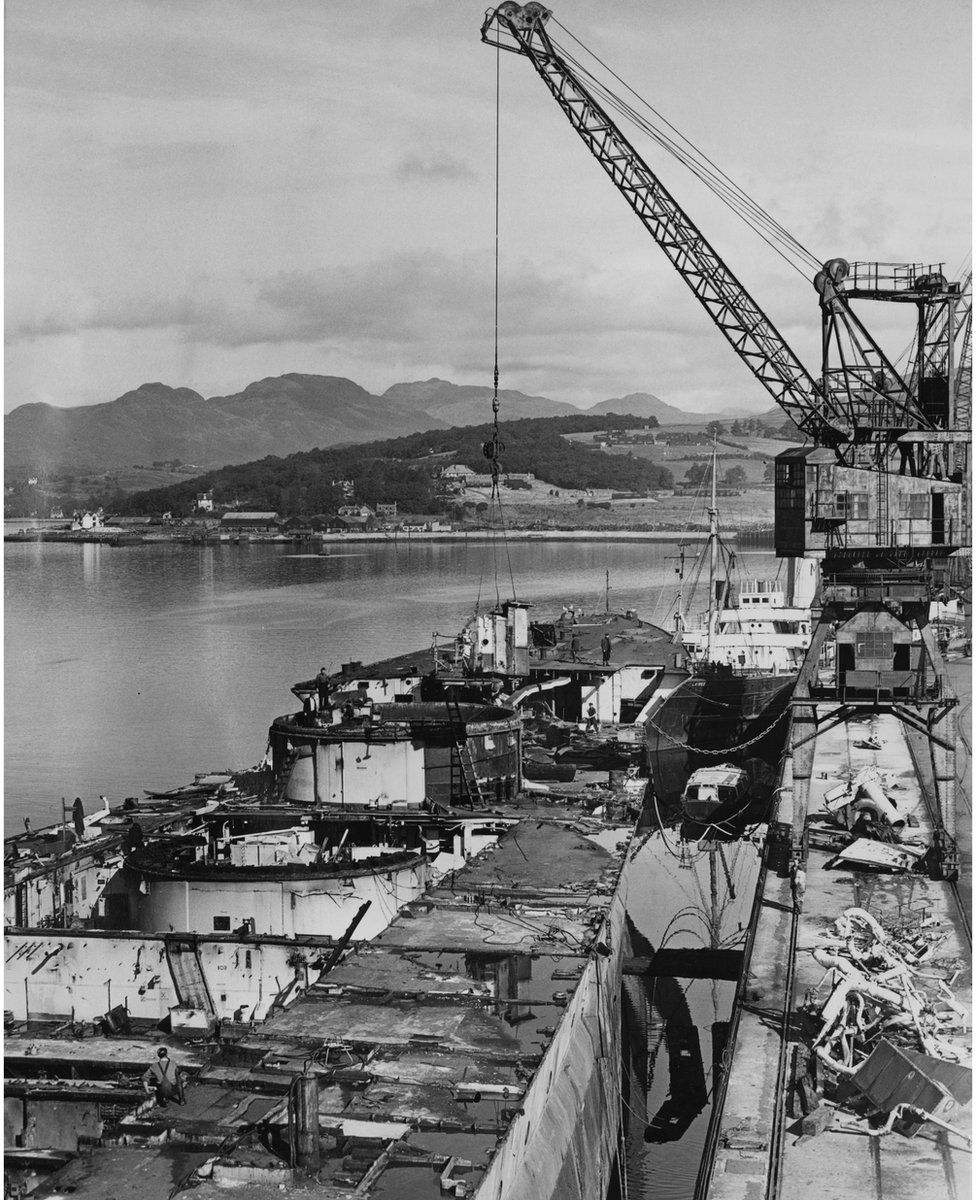 A shell hoist from the forward B twin 15-inch (381 mm)gun turret on the broken hull of the Royal Navy Renown-class battlecruiser HMS Renown is lifted away whilst in the process of being scrapped at the Metal Industries Ltd shipbreaking yard on 4 September 1950 at Gare Loch, Faslane, Scotland, United Kingdom