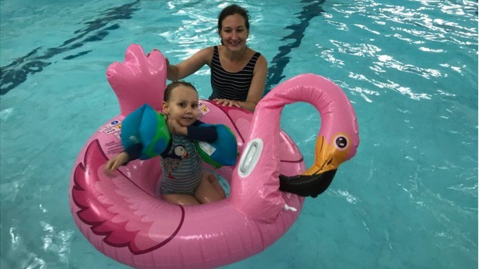 A young child on an inflatable with her mother