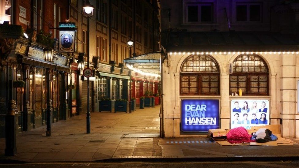 Homeless people sleep outside a theatre in central London