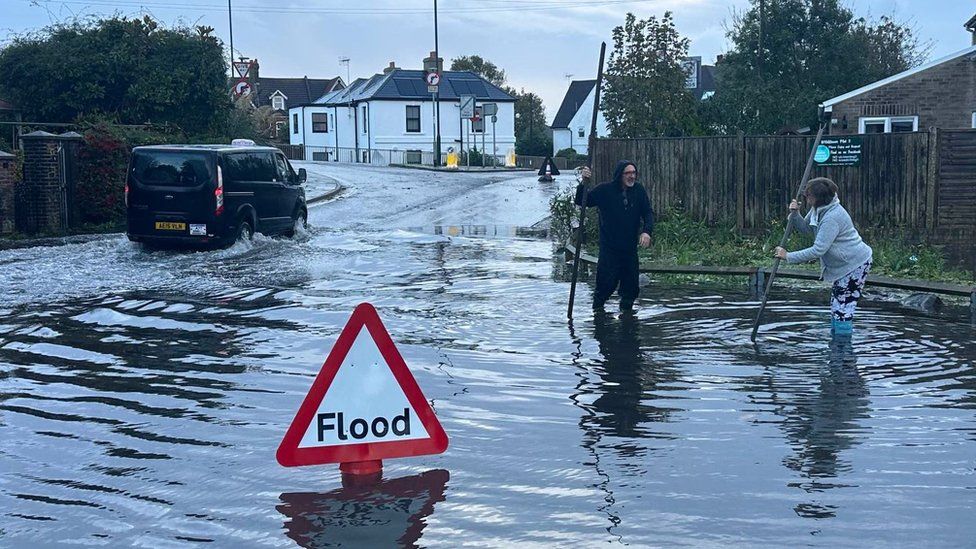 Two residents in London Road, Bognor Regis, try and find drains with large sticks