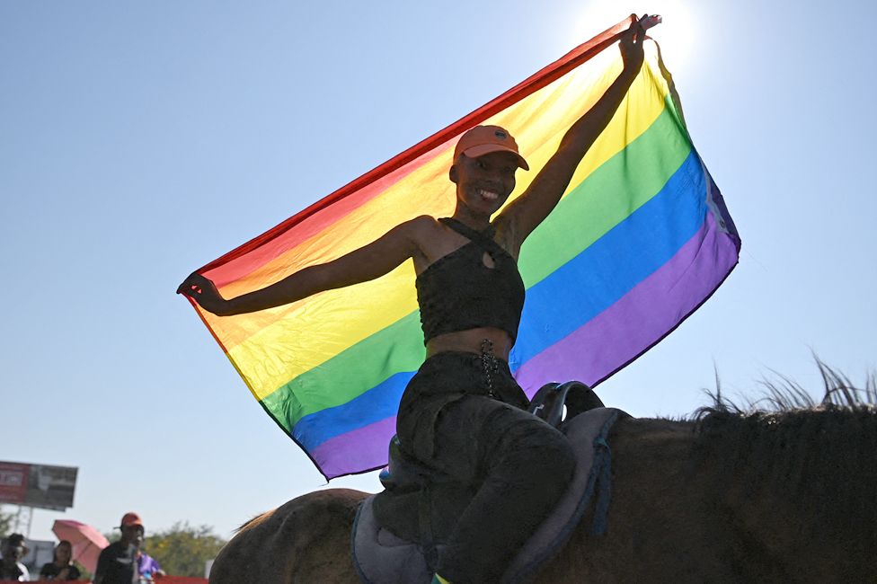 A gay pride participant holding a rainbow flag and riding a horse in Gaborone, Botswana - Saturday 7 October 2023