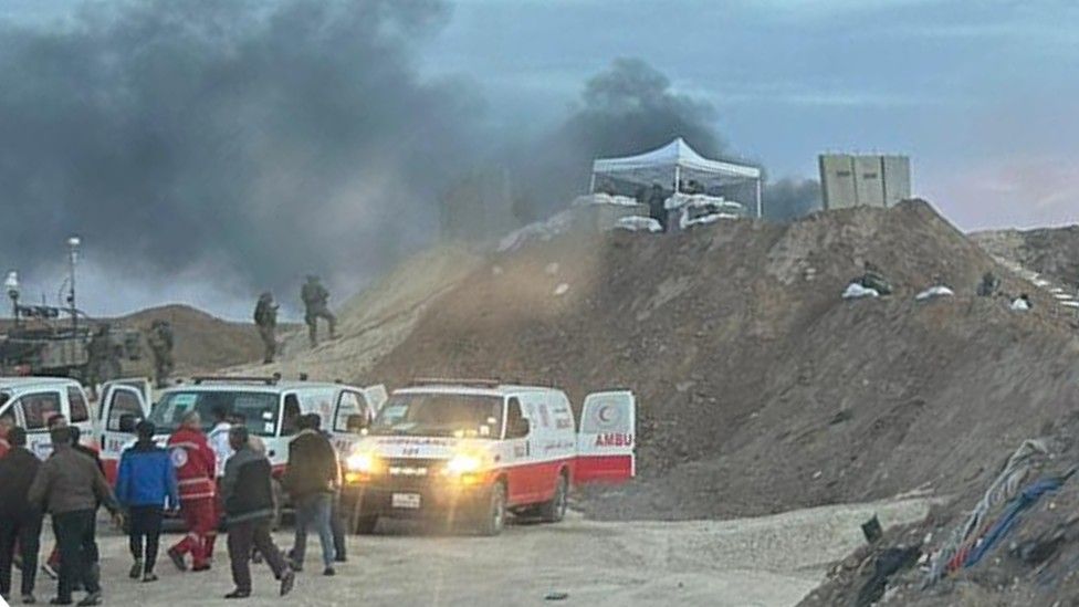 People - including soldiers - stand near a group of ambulances in the Gaza Strip