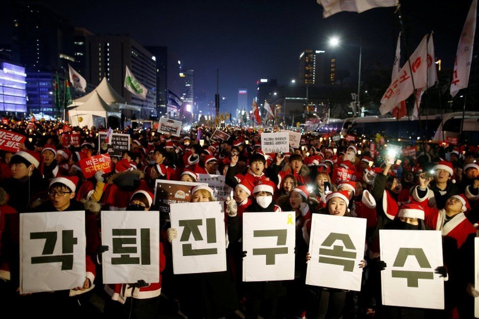 People dressed in Santa's costumes attend a protest demanding South Korean President Park Geun-hye's resignation in Seoul, South Korea, December 24, 2016. The banner reads "Resign immediately, Arrest investigation".