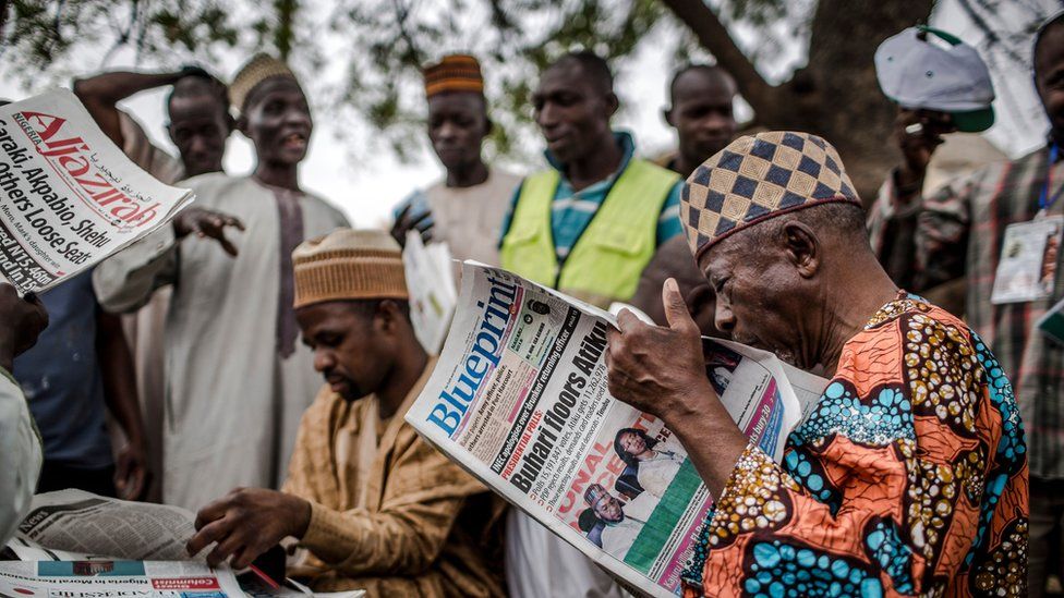 Man reads newspaper announcing election result in Kano, Nigeria