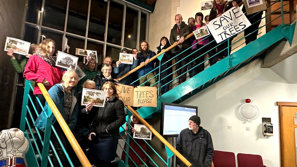 A group of people standing on the stairs holding signs