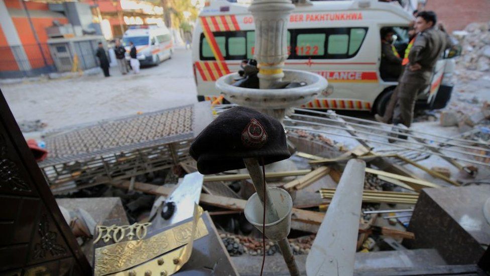 Полицейский берет (С) среди обломков на месте происшествия через день после взрыва бомбы смертника в мечети в полицейских участках в Пешаваре