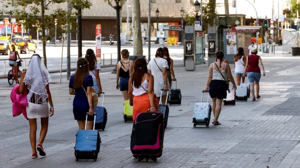 Tourists drag luggage through Barcelona