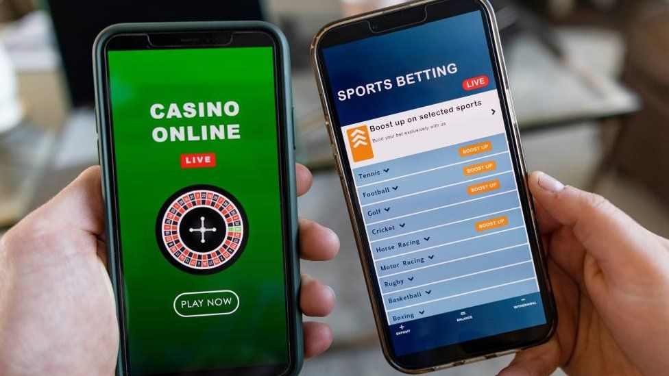 File image of hands holding smartphones, the screens of which show gambling apps