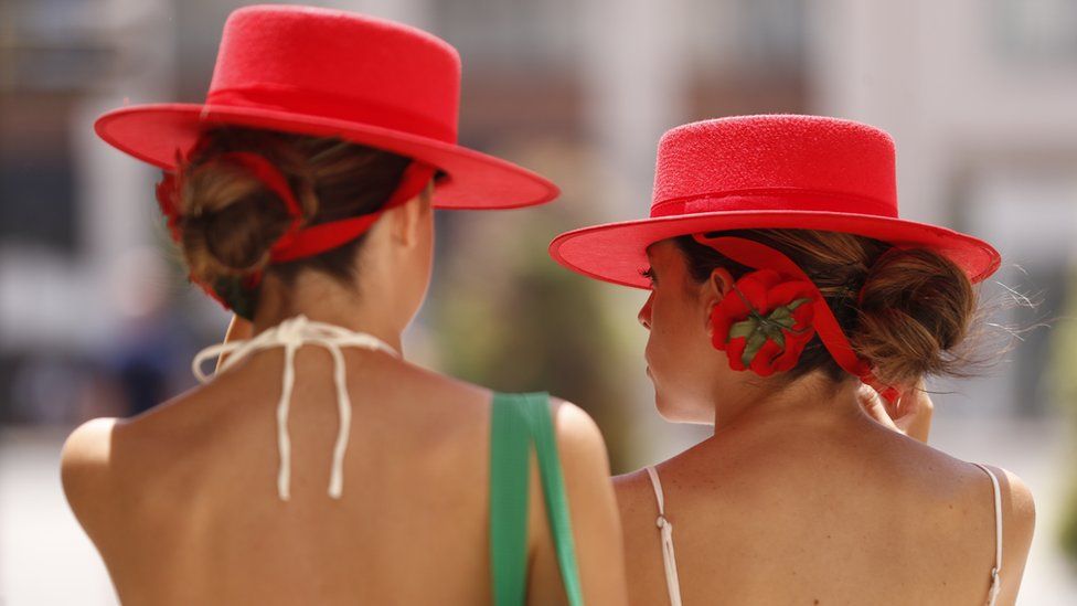Two women wear hats to protect themselves from the sun in Malaga