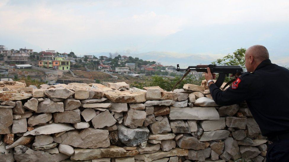 An Albanian police officer secures the perimeter of a house in Lazarat, a village known as Europe's cannabis capital, south of the Albanian capital Tirana, on June 18, 2014