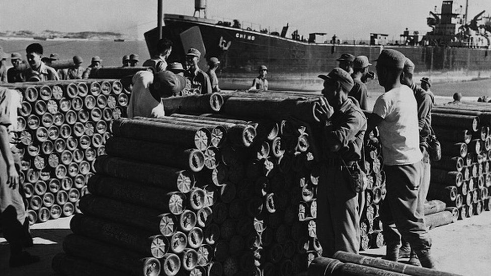 Солдаты складывают артиллерийские снаряды в морском порту на Quemoy, чтобы защититься от коммунистической китайской агрессии