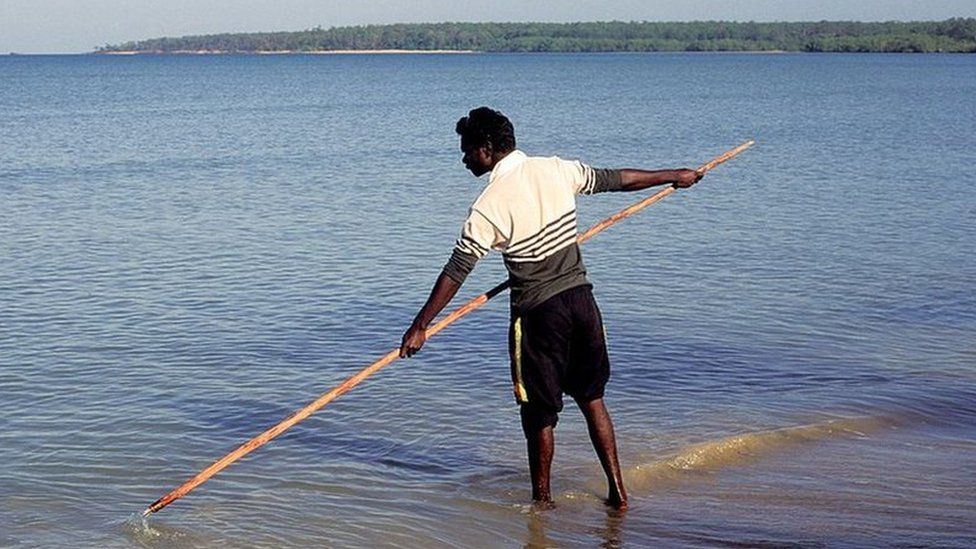 Мужчина из Тиви ловит рыбу тростью.