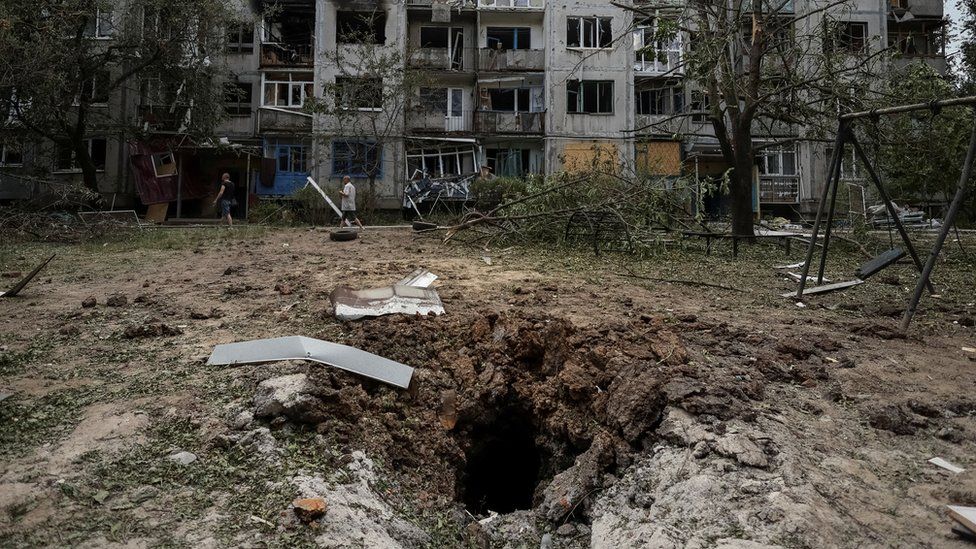 Local residents walk in front of an apartment building destroyed in a missile strike, amid Russia's invasion of Ukraine, in Bakhmut on 13 June