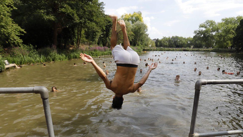 A bather jumps into the pond on Hampstead Heath, London