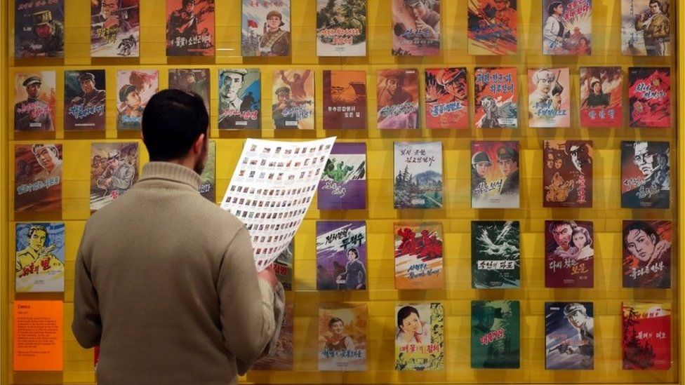 A man looks at comic book covers.