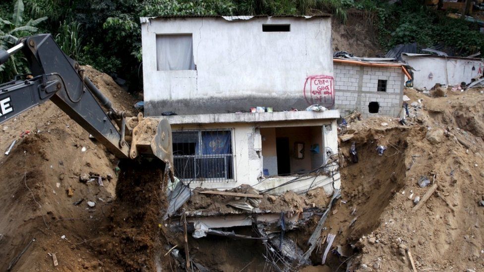 Heavy machinery remove dirt from an area affected by a mudslide in Santa Catarina Pinula, on the outskirts of Guatemala City, October 4, 2015.