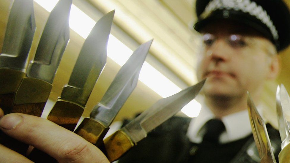 An officer holds knives handed in to police