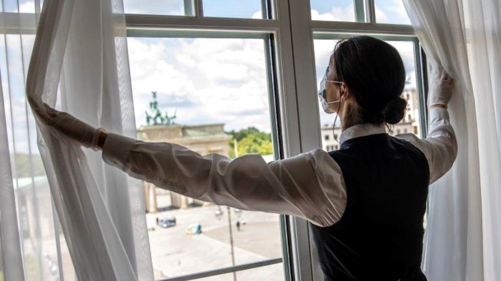 Housekeeper opening curtains in a Berlin hotel, May 2020