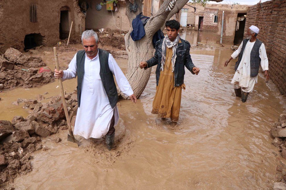 Afghanistan - people wade through flood water in Herat