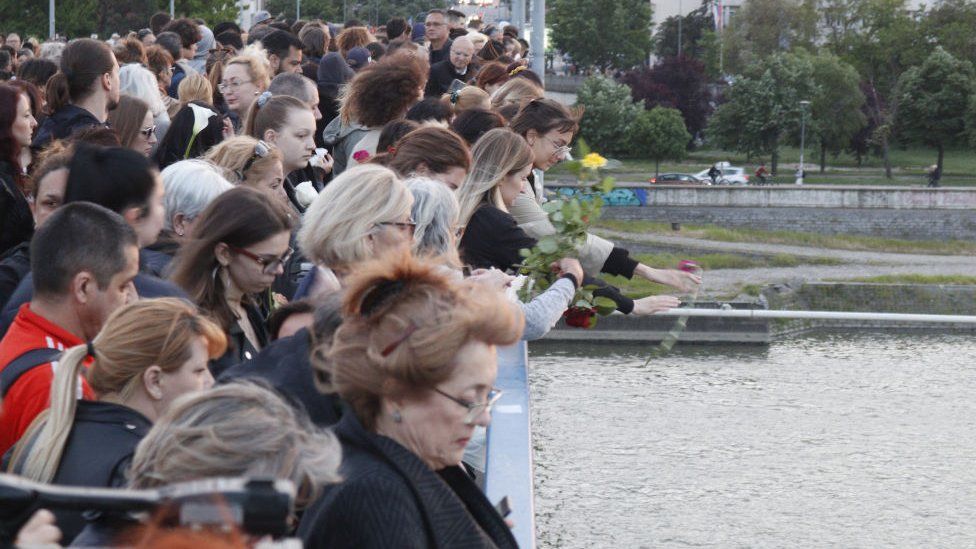 People throw roses into the Danube river